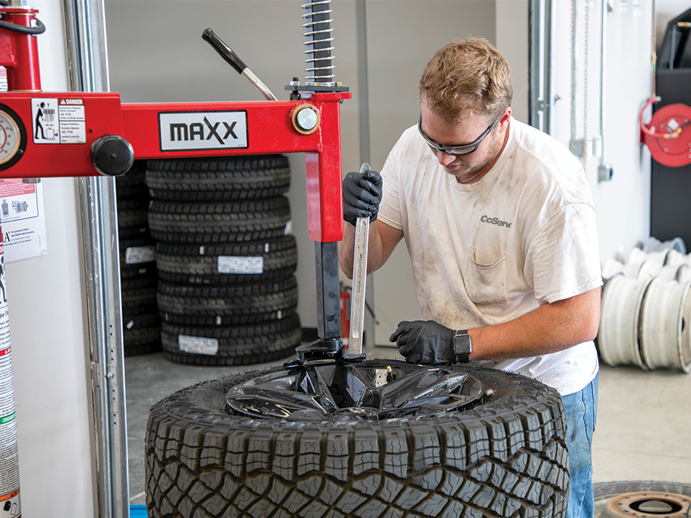 Tyler Garrett mounts a new tire on a rim.